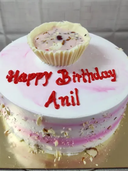 A birthday cake for Anil, featuring a fusion flavor. The top is decorated with a white chocolate cup filled with a creamy dessert.