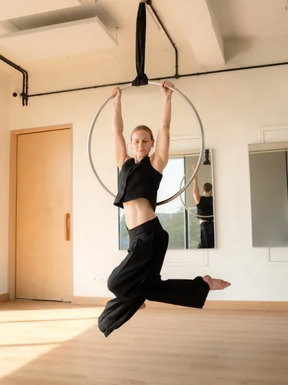 A strong pose on the aerial hoop, demonstrating the core and upper body strength developed through lyra training. This is a foundational position from which many other tricks begin.