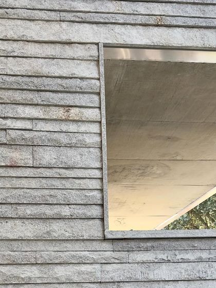 A window opening set within a textured stone wall, a simple frame for a view.