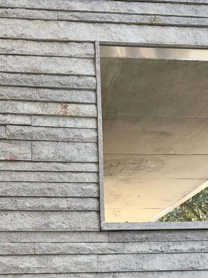 A window opening set within a textured stone wall, a simple frame for a view.