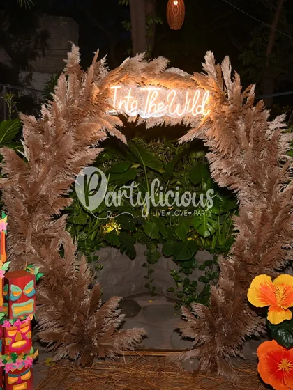 A closer look at the 'Into the Wild' neon sign nestled in a pampas grass arch, creating a stunning focal point for the event.
