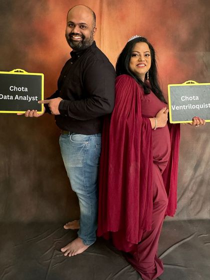 A beautiful maternity photoshoot picture with my husband. We're holding signs for 'Chota Data Analyst' and 'Chota Ventriloquist', dreaming about our daughter's future.