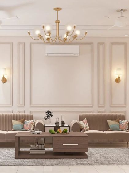 A living room that exudes classic elegance. The wall is treated with intricate molding, complemented by traditional sconces and a grand chandelier. The plush, neutral-toned sofas complete the sophisticated look.
