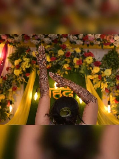 A creative pose highlighting the bride's mehendi, set against our floral and fabric backdrop. The warm lighting from the Edison bulbs adds a modern touch to the traditional setup.