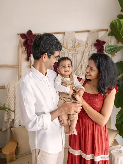 A happy family of three, with their baby boy smiling brightly.