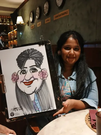 The background of the restaurant with its wall of clocks added a nice touch to this photo. She was very happy with her caricature.