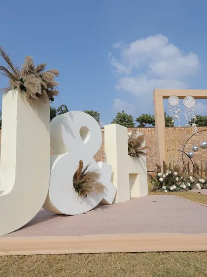 Large, custom-made initial letters of the couple, decorated with pampas grass, serving as a personalized and modern photo backdrop.