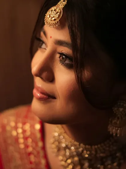 A close-up portrait capturing the bride's beautiful features and the golden glow of her jewelry. This is pure bridal elegance.