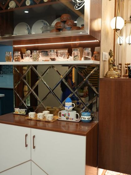 This crockery unit combines open and closed storage, with a mirrored backsplash and under-cabinet lighting. It's a perfect blend of functionality and decorative flair for a dining area.