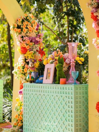 A whimsical and colorful decor detail. A mint green console table is adorned with a variety of flowers and quirky props like a green rabbit and a vintage telephone.