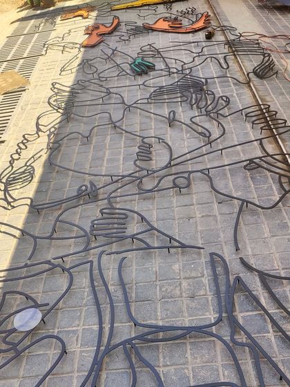 The raw, unpainted metal framework for the 'fun and frolic' installation laid out on the ground. This shows the first step in our process, translating a linear drawing into a physical metal form.