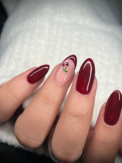 A close-up of the cute, hand-painted cherry accent nail. The detail is precise and adds a fun, personal touch to the manicure.