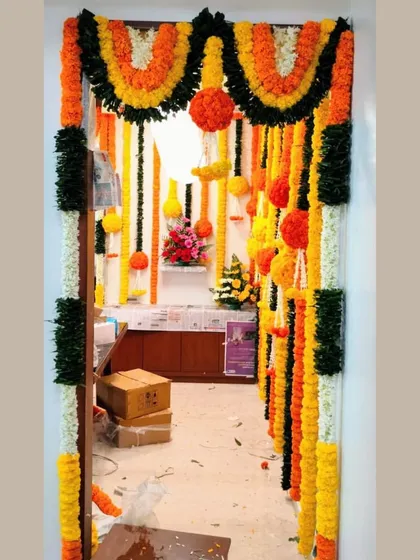 This traditional entrance decoration uses multi-colored marigold garlands to create a layered and festive look. The design includes hanging floral balls and torans for an authentic celebratory feel.