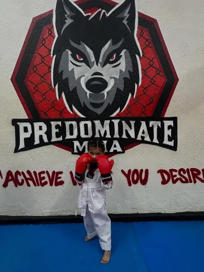 Mini warriors in training. A young girl in her Taekwondo uniform and boxing gloves stands ready, showcasing the fighting spirit we nurture.