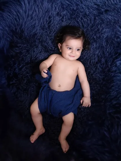 A minimalist portrait focusing on the baby's sweet expression. The simple setup with a deep blue, fluffy rug creates a beautiful contrast and keeps the focus on the child.