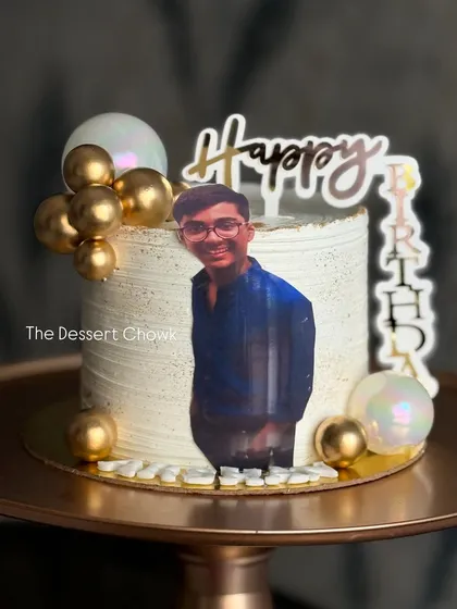 A modern tall cake with a personal photo, decorated with gold and pearl bubbles for a stylish birthday celebration.