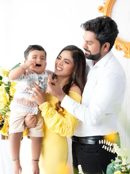 A candid and playful family moment. The parents share a laugh while their toddler makes a funny face, showing the real and unscripted joy that makes family photos so special.
