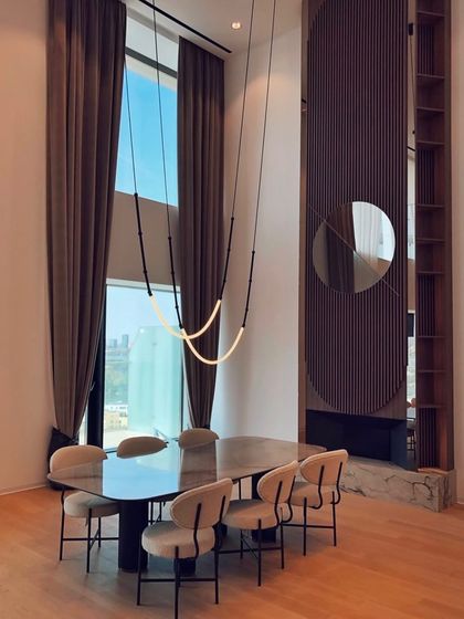 The Leda system is seen here in a dining room with double-height windows, its graceful curves adding a soft, organic touch to the grand space.