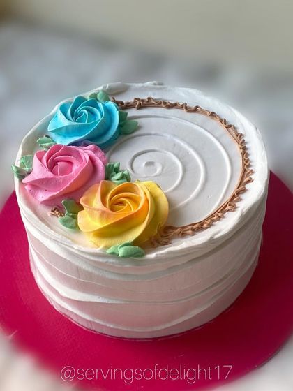 A simple white cake adorned with a rainbow of buttercream roses. This design is timeless and perfect for any happy occasion.