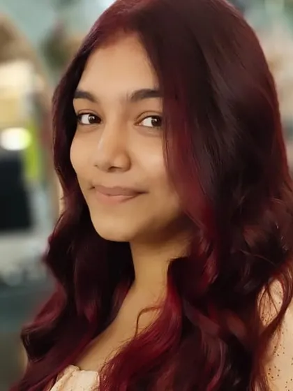 A close-up portrait showcasing the rich tones of her new red hair colour. The soft waves add a touch of glamour.
