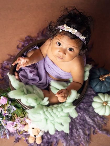 An overhead view of this sweet baby in a bowl, looking up with her big, beautiful eyes during her six-month milestone session.