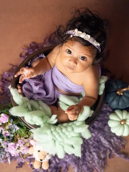 An overhead view of this sweet baby in a bowl, looking up with her big, beautiful eyes during her six-month milestone session.