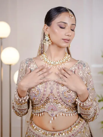 The model showcasing the intricate blouse of the beige lehenga. The pearl drop details add a touch of elegance.