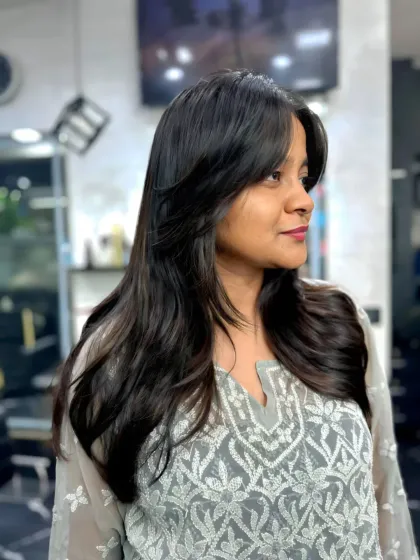 A side profile of a beautiful layered haircut with face-framing bangs. This style is designed to flatter the face and add softness to the overall look.