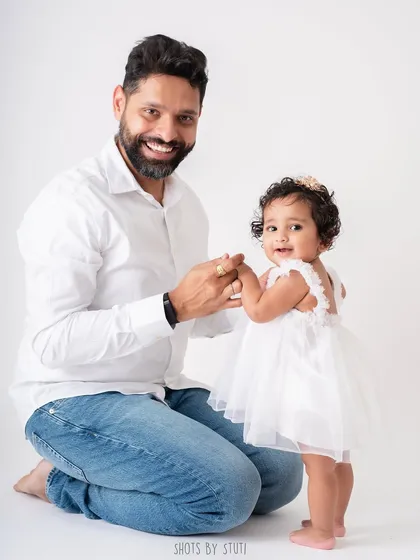 A father holding his daughter's hand as she learns to stand. It's a beautiful metaphor for the supportive and guiding role he'll play in her life.