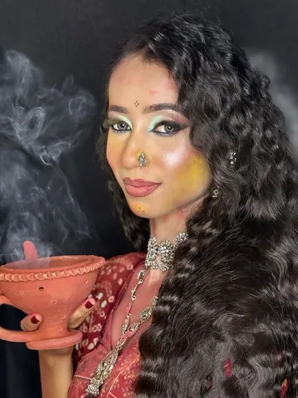 A portrait from the Holi shoot, with the model holding a traditional incense burner. The makeup is designed to look beautiful even with smudges of festive color.