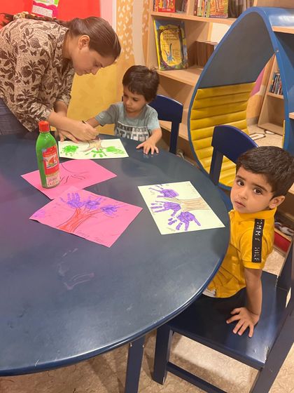 Here I am helping a child with their handprint art. These activities are not just about the final product, but about the process of creating, feeling the paint, and seeing their own hands make something new.