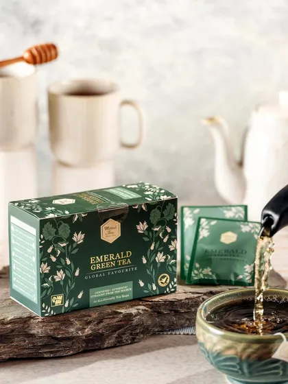 A bright and clean action shot of Mittal's Emerald Green Tea being poured. This image feels fresh and healthy, perfect for promoting the wellness aspects of green tea.