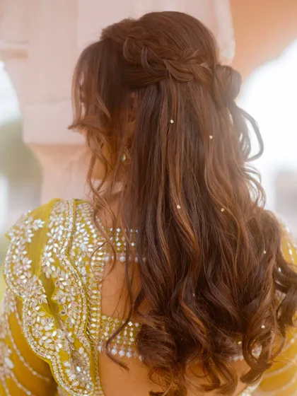 A detailed look at the bride's half-up hairstyle for the carnival, adorned with delicate pearls.