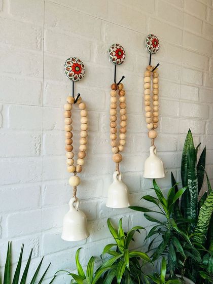 A beautiful set of three classic white boho beaded ceramic bells. The natural wooden beads and jute twine give these bells a rustic and bohemian feel, perfect for creating a serene and stylish atmosphere.