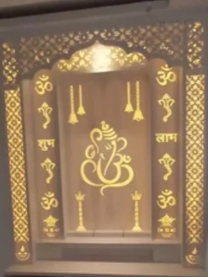 This backlit mandir showcases a large Ganesha motif at its center, surrounded by "Om" and "Shubh Labh" symbols. The entire structure is framed with jali-cut panels, creating a warm and inviting glow perfect for a home prayer corner.