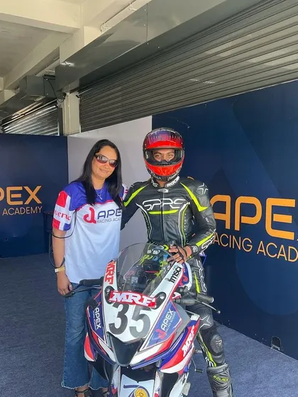 The support system is everything. A rider in full gear poses with a team member next to his race-prepped Yamaha R15 inside the Apex Racing Academy pit garage.