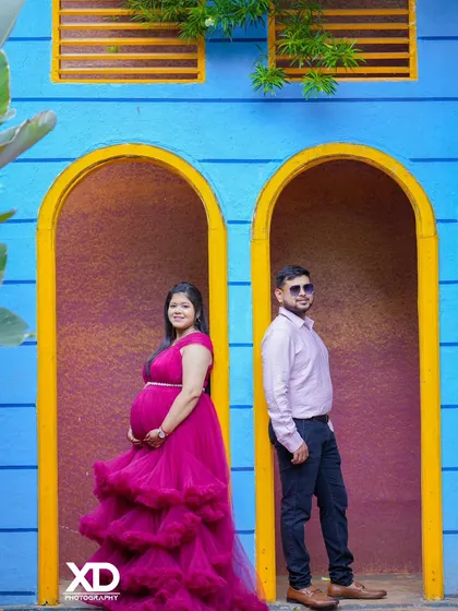 A creative composition with the couple posing in separate arched doorways against a bright blue wall.