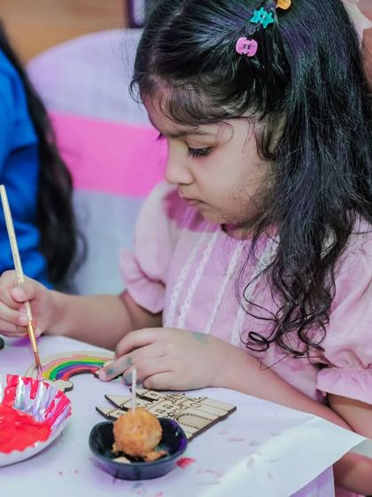 A child painting a wooden cutout. I provide a variety of shapes and themes for painting activities, from animals to superheroes.