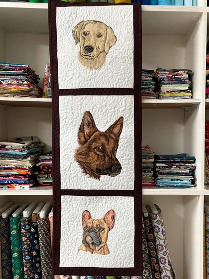 Immortalize your furry friends with a custom pet portrait quilt. This wall hanging features detailed, embroidered portraits of three different dogs, capturing their unique personalities in a beautiful piece of textile art.