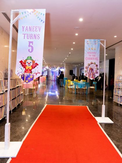 A red carpet walkway flanked by personalized banners, welcoming guests to the carnival.