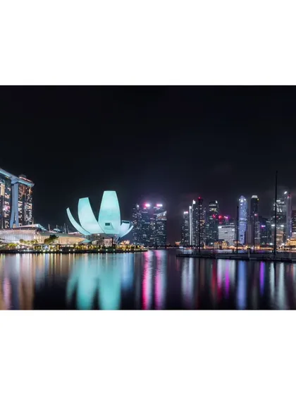 A beautifully composed wide shot of the Marina Bay skyline in Singapore at night, showcasing its famous landmarks.