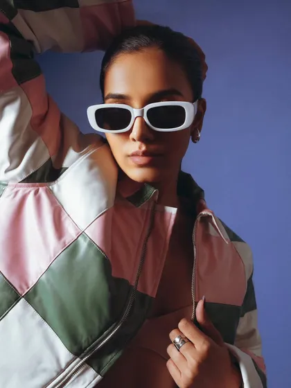 A close-up on a patchwork jacket, highlighting the color-blocking and texture. The cool sunglasses add a stylish flair, making the product feel trendy and desirable.