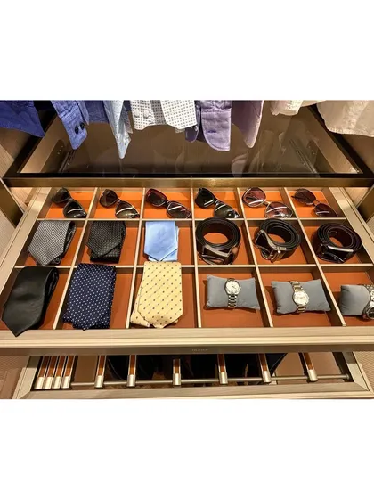 A pull-out drawer with custom, leather-lined compartments for a gentleman's accessories. Watches, sunglasses, and ties each have a designated spot, making the morning routine seamless.