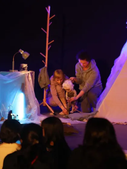 An intimate scene from 'Sea of Possibilities', where the puppeteers tenderly care for the main character, drawing the audience into the story.