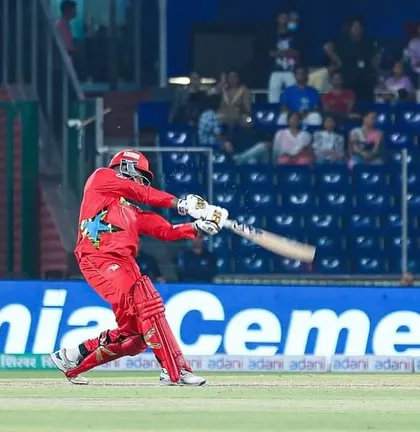 Dhruv Singh playing a powerful shot in a stadium filled with spectators. This is the stage we prepare our players for.