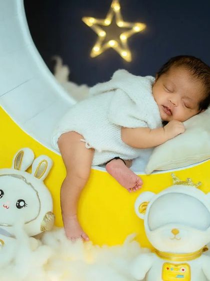 This image highlights the textures used in the setup, from the knitted baby outfit to the fluffy clouds, all contributing to a visually rich and gentle portrait.