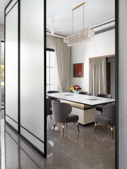 This formal dining room is defined by its elegant simplicity. A contemporary chandelier hangs over a marble-topped table, and frosted glass panels can be used to create a more intimate setting when desired.