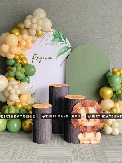 A minimalist and chic safari theme, perfect for a modern first birthday. The design uses two backdrops, log-style plinths, and a simple balloon garland in muted greens and creams.