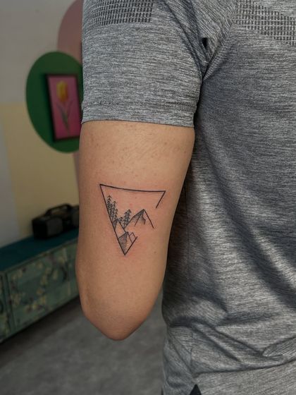 Another view of the geometric mountain tattoo, showing its placement on the bicep. It's a clean, modern, and stylish piece.