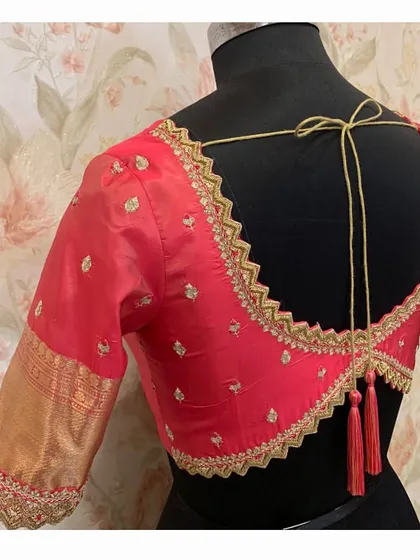 A red silk blouse with a deep, zig-zag cutwork back, all edged with gold embroidery and finished with elegant tassels.